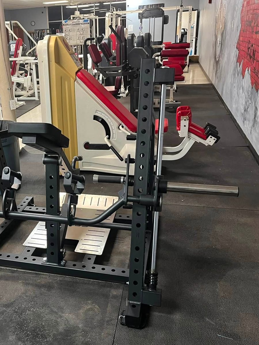 Plate-loaded strength machines and a 45-degree leg press on the Iron Forge Fitness training floor